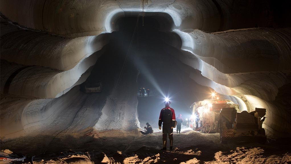 An employee uses the light from a head torch to illuminate the machine cut walls of a potash mine operated by Uralkali, in Russia
