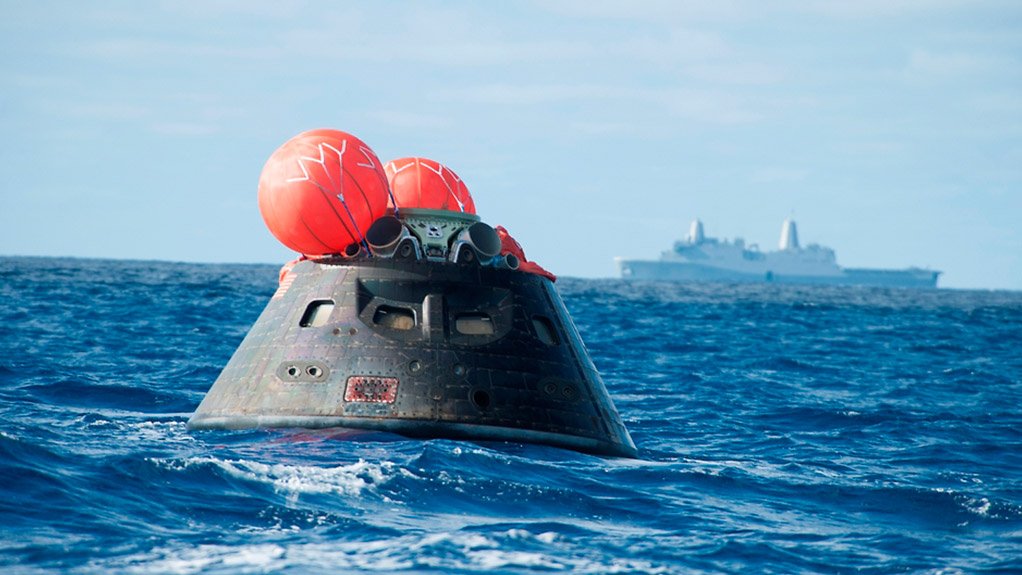 The Orion capsule after splashdown with recovery ship USS Anchorage in the background