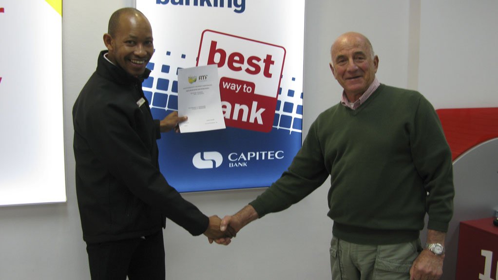 HANDS ON Khaya Lam project manager Perry Feldman handing over title deed to Capitec employee, which was paid for by the bank itself 