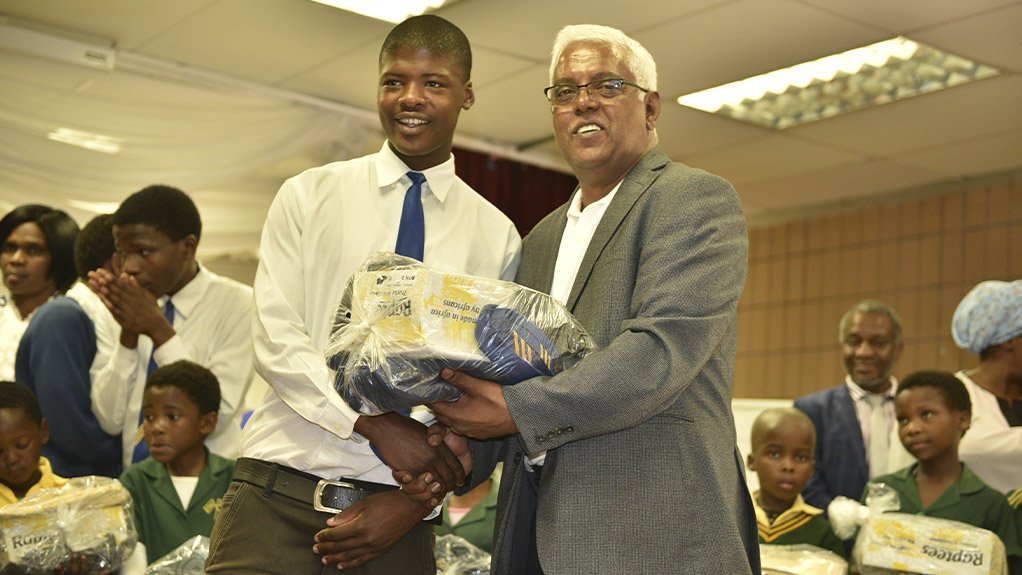 KZN Finance MEC Ravi Pillay handing over a uniform pack to Zwanani Gumede, a grade 10 pupil at Phindavele High School