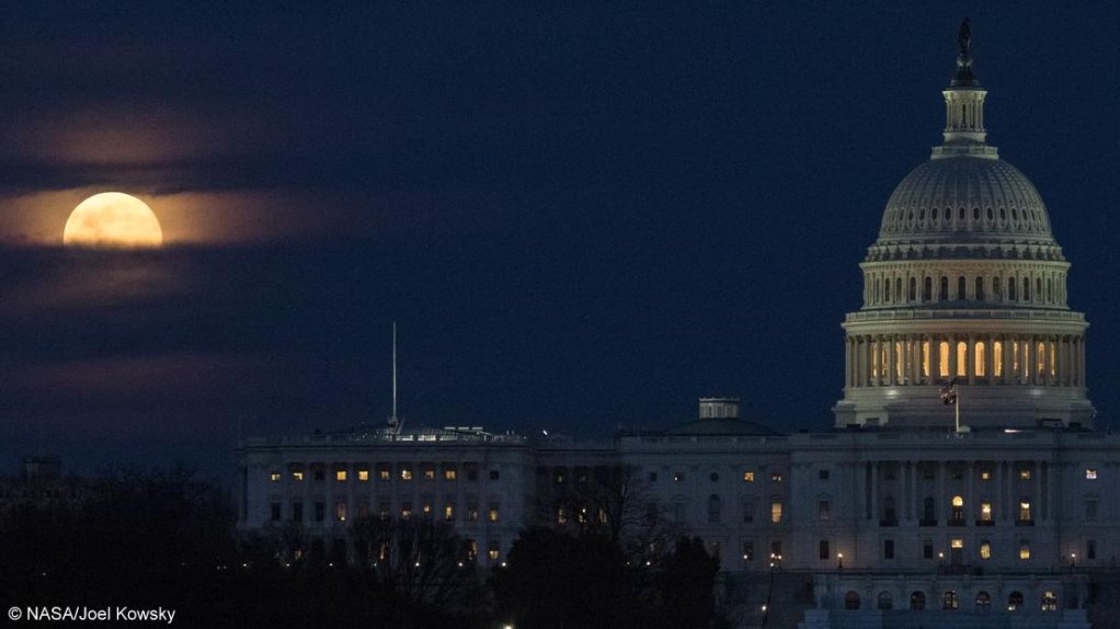 The Moon is seen as it rises behind the US Capitol.