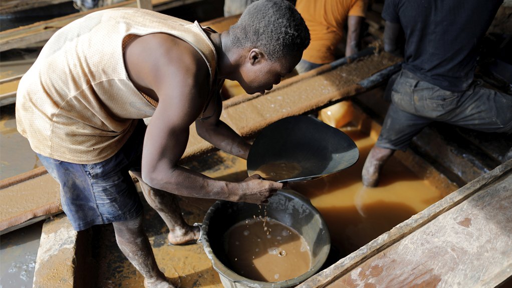 An artisanal miner pans for gold in alluvial sediment over a plastic bucket at the unlicensed mining site of Nsuaem Top in Ghana

