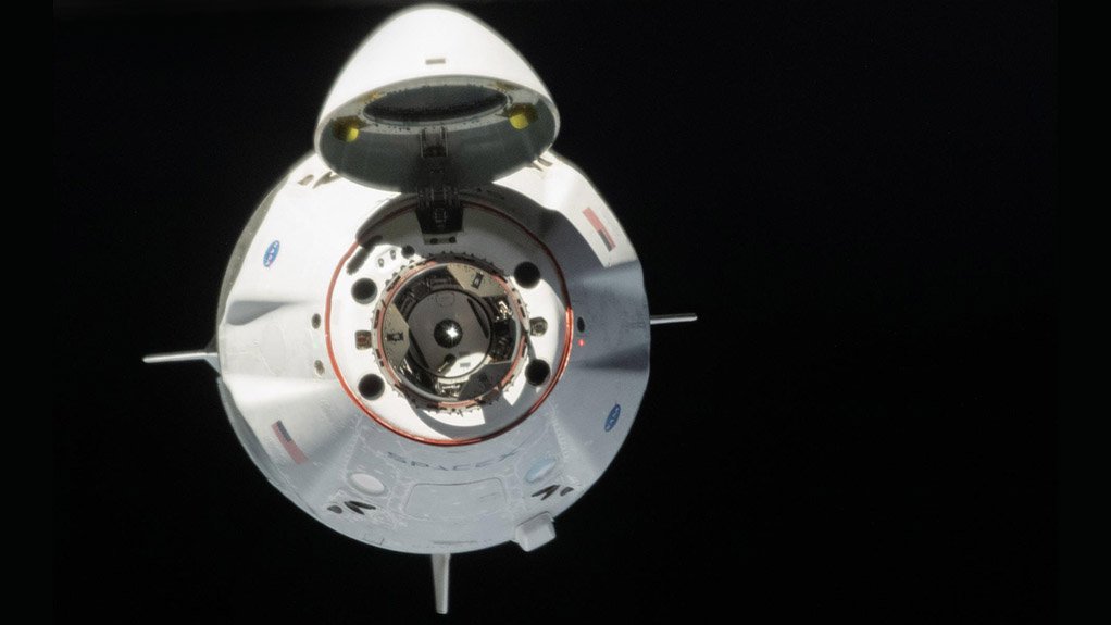 RENDEZVOUS: The Crew Dragon spacecraft about to dock with the ISS, with its nose cone open showing its docking attachment points and airlock hatch.
