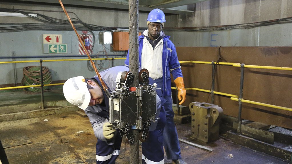 WearCheck technician Roger Henwood (a SAQCC RCA Level 2 senior rope inspector) uses a magnetic rope test instrument to test the integrity of steel wire rope. Looking on is a rigger assistant from the mine.
