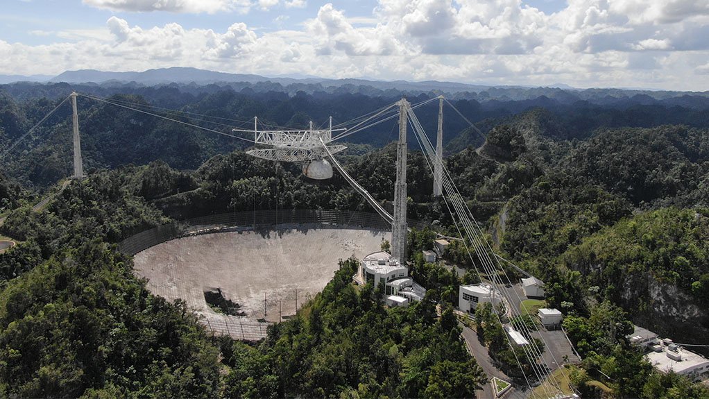The Arecibo radio telescope, photographed after the first main cable break in November but before the fall of the suspended instrument platform. Damage to the dish is clearly visible. 