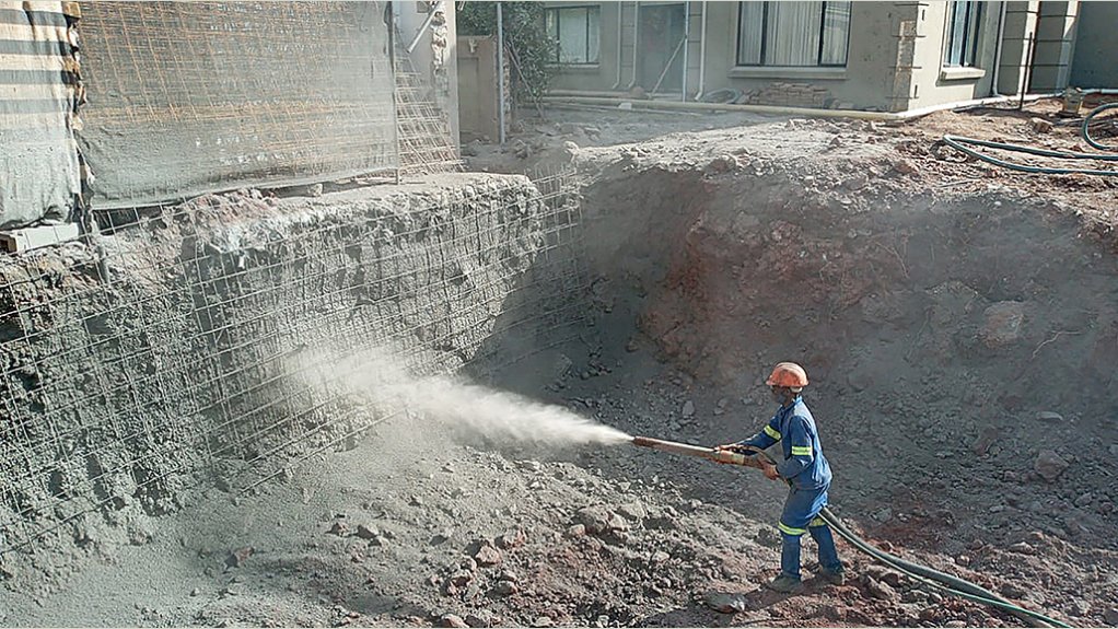 Gunite, a mixture of cement, sand, and water, being applied to the sinkhole walls by pressure hose.