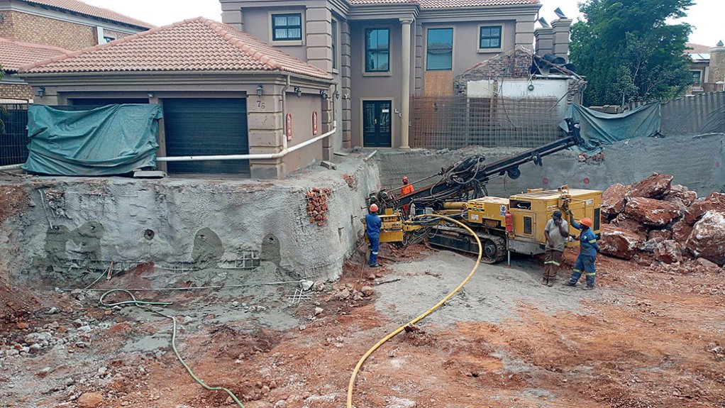 Drilling of soil nails into the sinkhole walls with Gauteng Piling’s special rig. Note the large rocks on the right in the background.