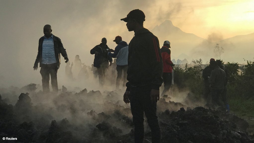 Residents walk near destroyed homes with the smouldering lava deposited by the eruption of Mount Nyiragongo volcano near Goma, in the DRC, May 23.