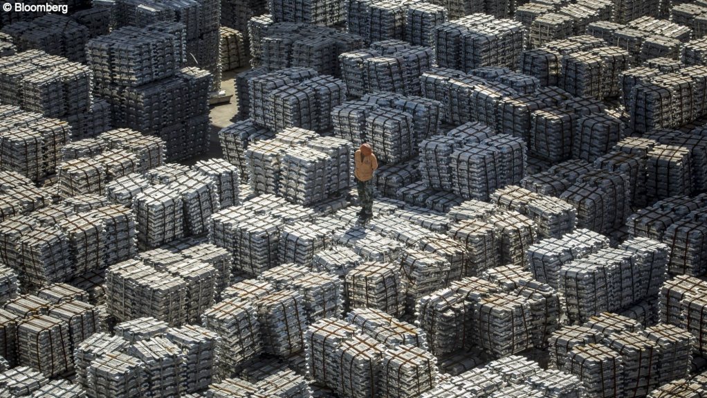 A worker stands on bundles of aluminum ingots at a China National Materials Storage and Transportation Corp. stockyard in Wuxi, China.
