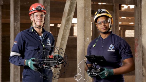 An image of two drone pilots, holding a drone and remote 