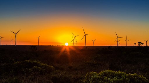 Image of sun rising behind wind turbines