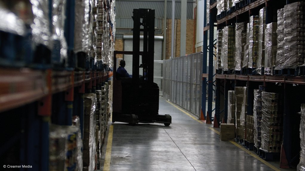 A photo of a forklift and driver operating in a shelved warehouse 