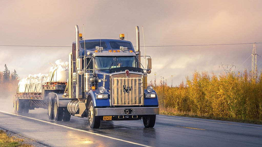 Blue truck driving on an open road.