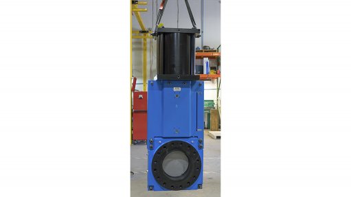 An image of a large blue high pressure valve used in tailings pipelines strung from a hoist