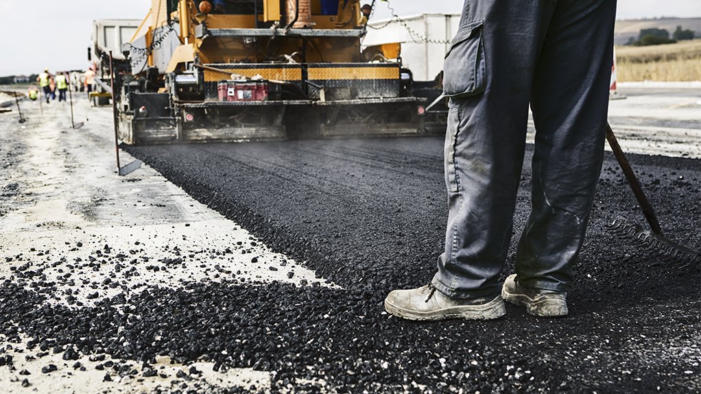 Image of man standing next to road being tarred