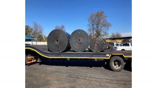 An image of conveyor belting being transported by a truck