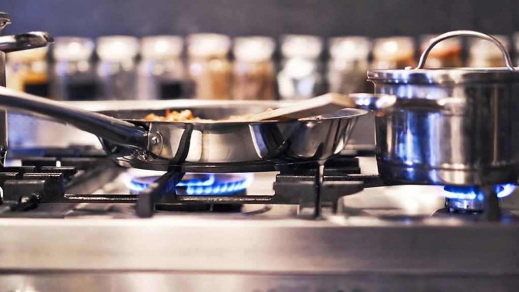 A stainless steel stove top with gas burners burning blue flame from an LPG gas supply, used for cooking