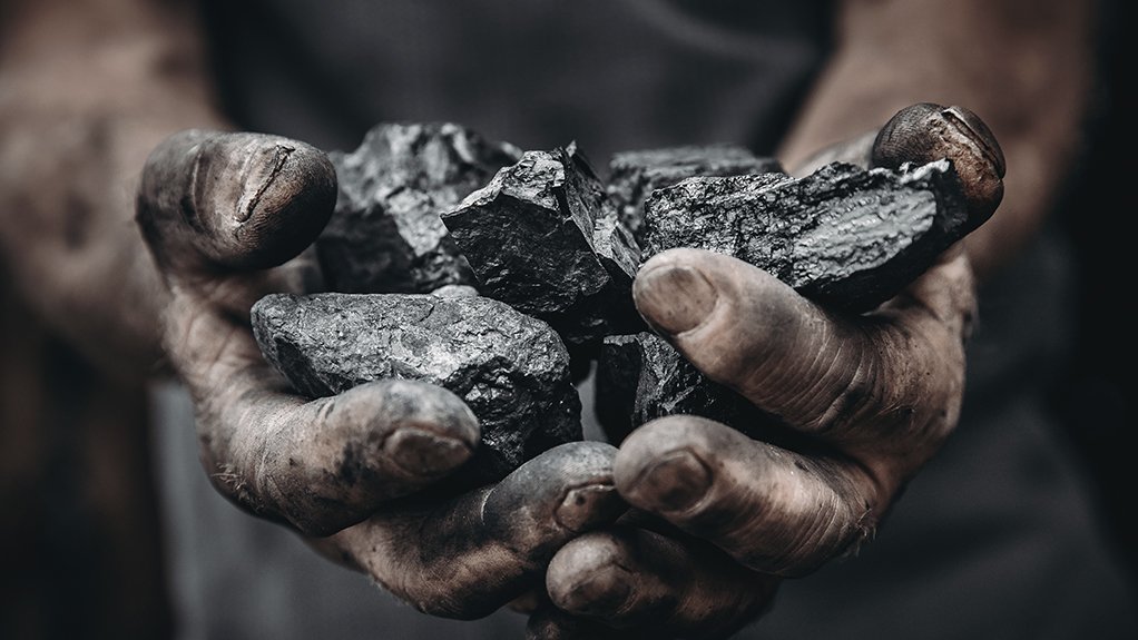 A photo of a miner holding coal in his hands