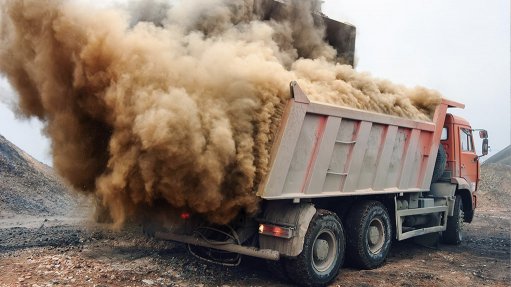 Image of sand blowing of the back of an open truck at a mine