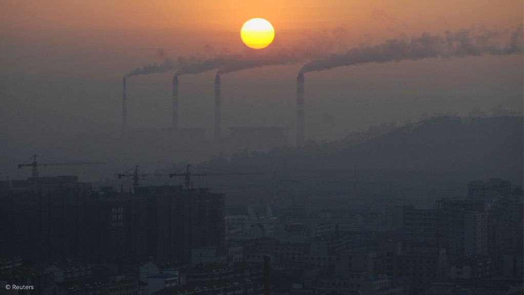 Image shows smoke stacks in front of a setting sun