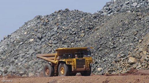 Image shows a dump truck in front of a nickel run-of-mine ore stockpile
