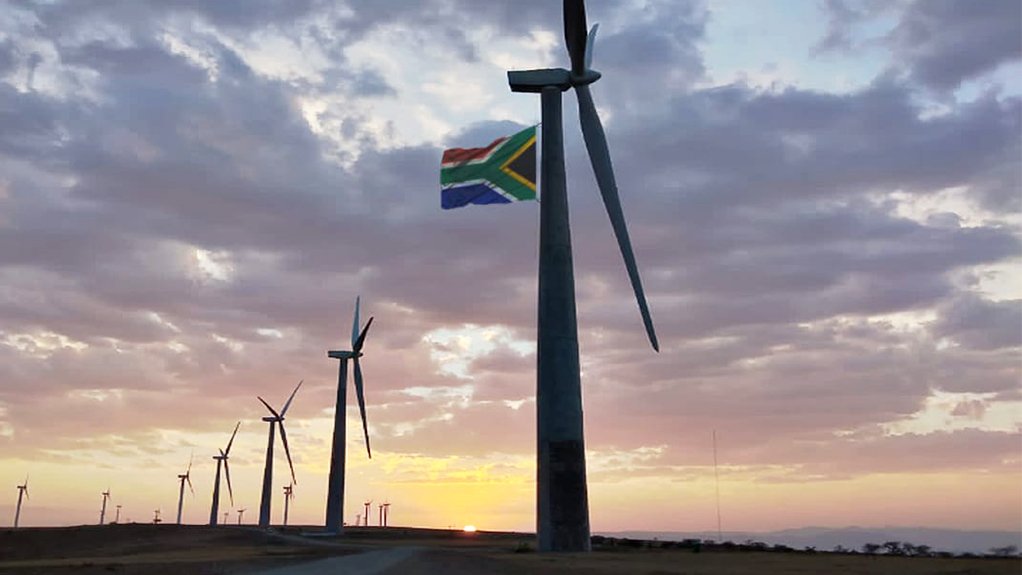 A photo of Nxuba Wind Farm turbines at sunset with a South African flag attached to one of the turbines