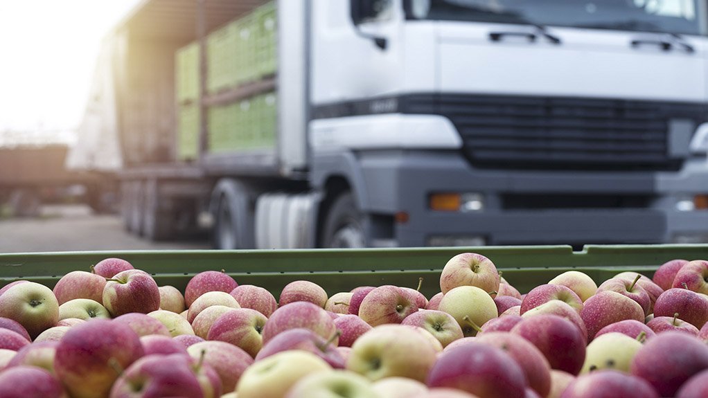 A photo of a pallet of apples with a truck in the background