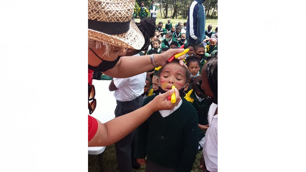 Image of Ejustley Boshoff, Coordinator of the Gender and Disability subsection, Community Services, draws a funny face with face paint on a child’s face at the event in Herold
