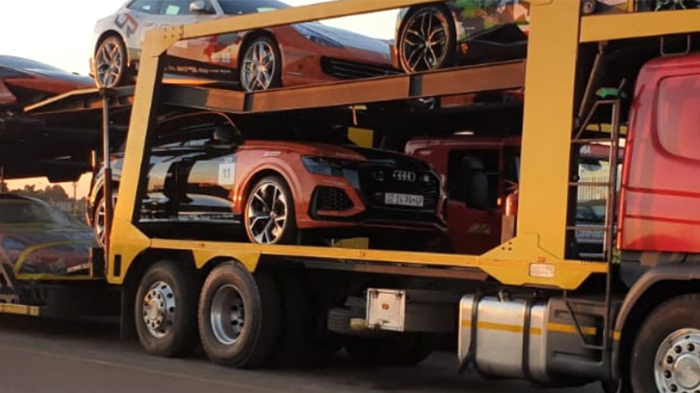 An image of cars being transported by truck