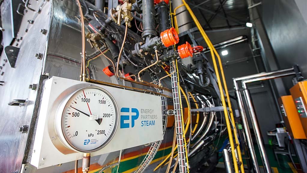 A large boiler with a circuit board attached with Energy Partners logo on, cables and pipes leading to and from the boiler at a chicken processing plant
