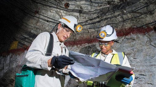 A photo of two female miners in PPE looking at a chart