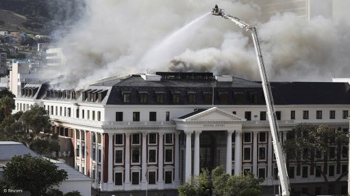 A photo of the parliament buildings on fire with firefighters working to extinguish the blaze
