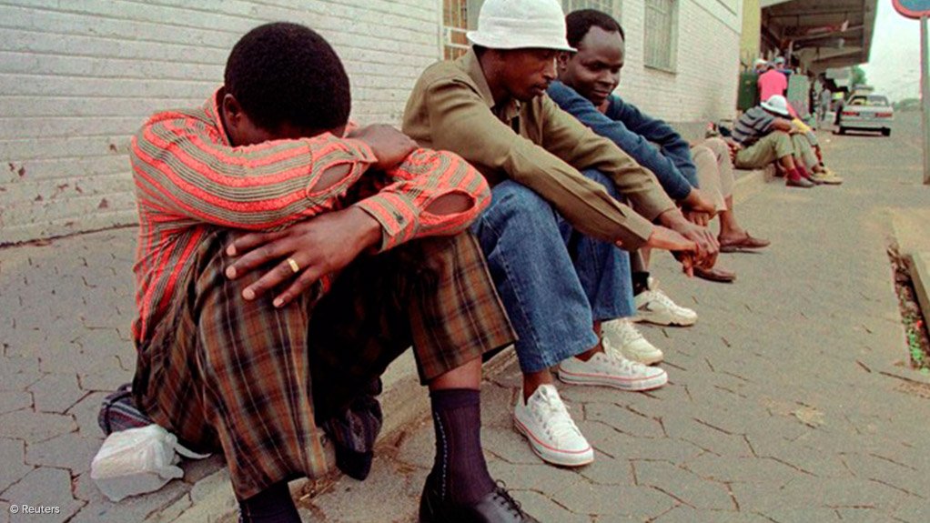 A photo of unemployed men sitting on the sidewalk