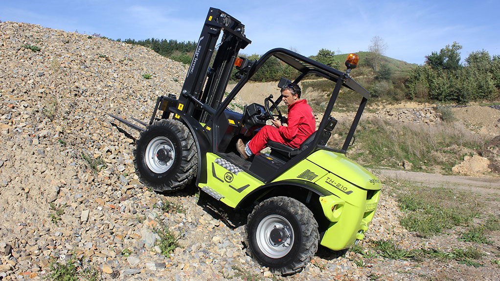Man operating a green and black forklift truck up a steep hill
