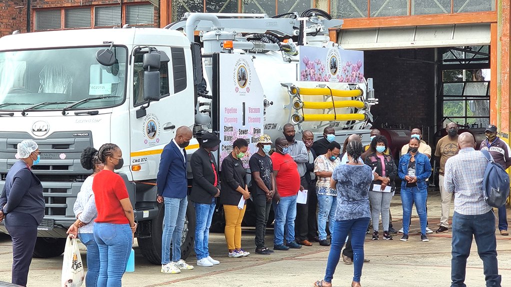 A large truck with a combination jetting and vacuuming capability in front of a group of staff and dignitaries at the hand over of the truck