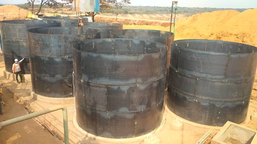 Large steel tanks with a man on site at the Buckreef oxide mill expansion project 