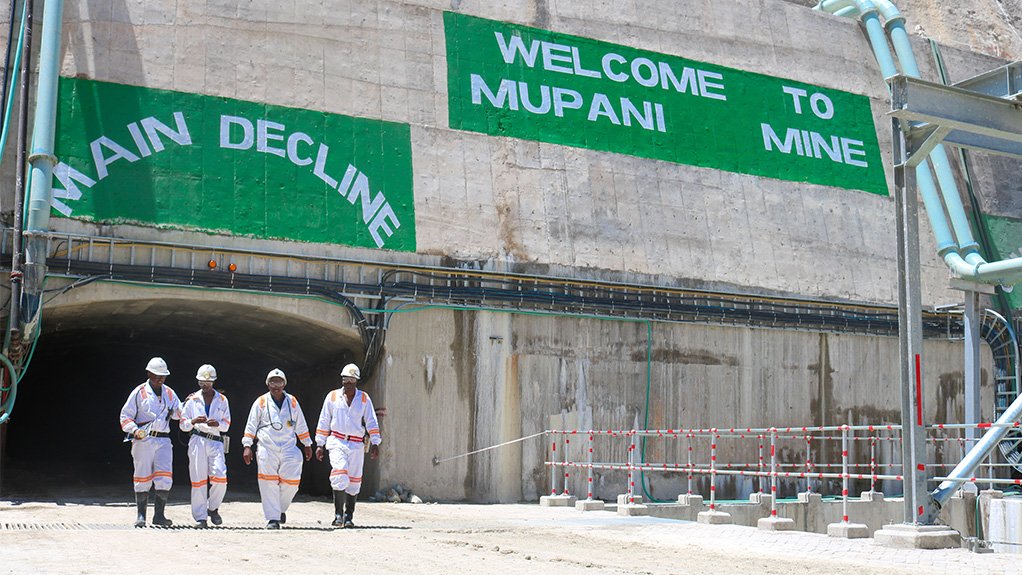 An image of four workers existing the access tunnel to the main decline of the Mupani mine development 