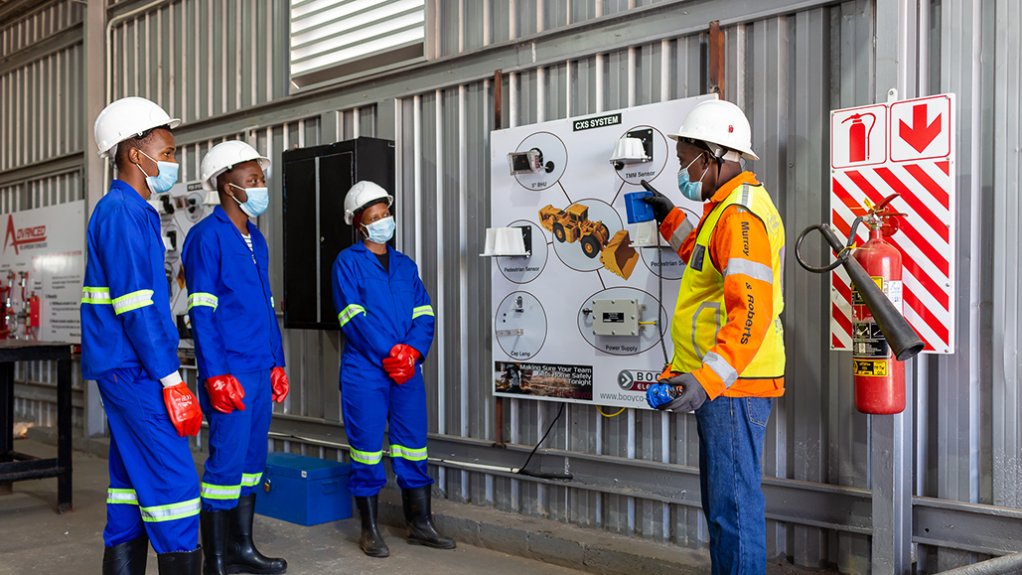 An image of three trainees and their instructor at the Murry & Roberts Training Academy, with the instructor pointing out how the Booyco Electronic CSX proximity  detection system works 