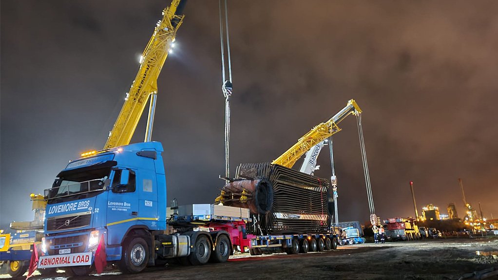 A night time photo of a large truck mounter crawler crane, lifting boiler plant elements for the refurbishment of a boiler plant at a paper mill in  South Africa