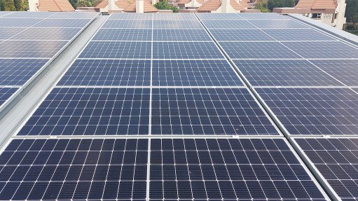 A large array of solar panels on the top of an office building 