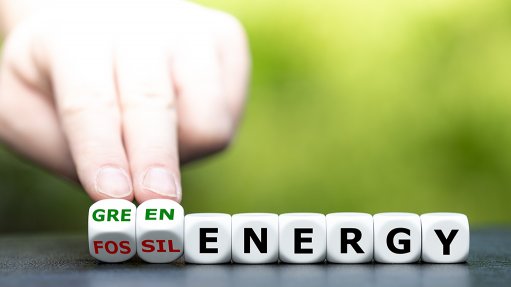 An image depicting a hand changing the term fossil energy into green energy written on dice