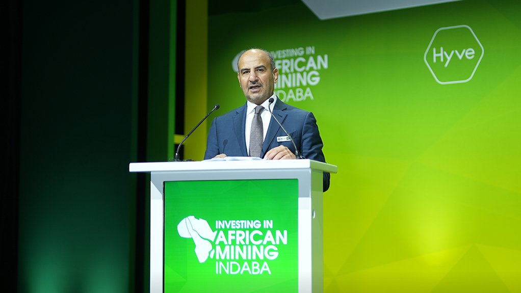 An image depicting Khalid Al-Mudaifer, standing on a green podium delivering a speech at the Mining Indaba