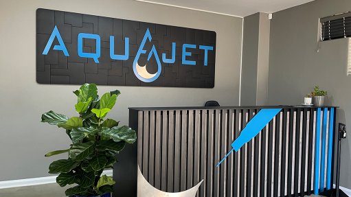 A brand-new front desk with metal lettering in blue and grey that say Aquajet, which was cut using an Omax waterjet cutter
Will select image

