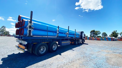 A number of 12-meter-long blue water pipes on a truck set for delivery at a water works