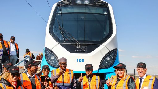 An image depicting Irene Charnley, Leonard Ramatlakane, David Makhura, Fikile Mbalula and other dignitaries in the transport and rail industries standing in front of the one-hundredth PRASA train