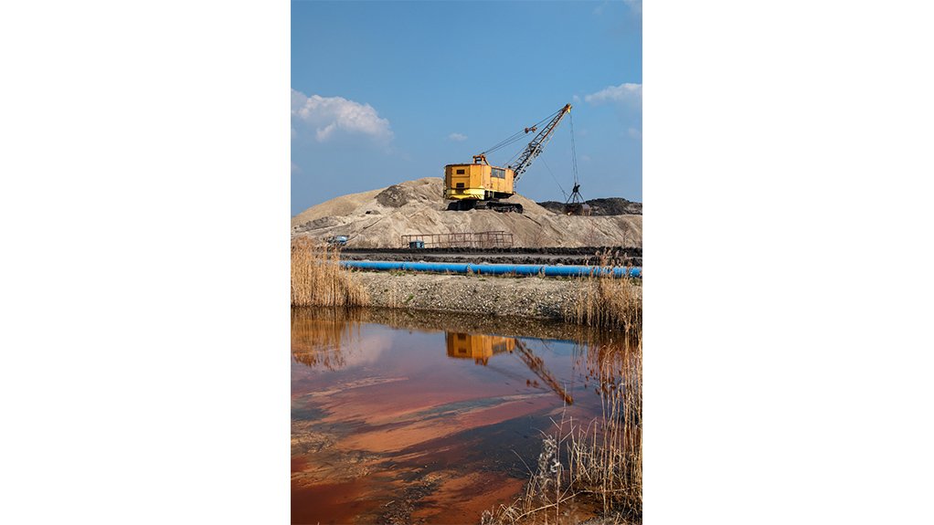A body of polluted or waste water in the foreground of a mine