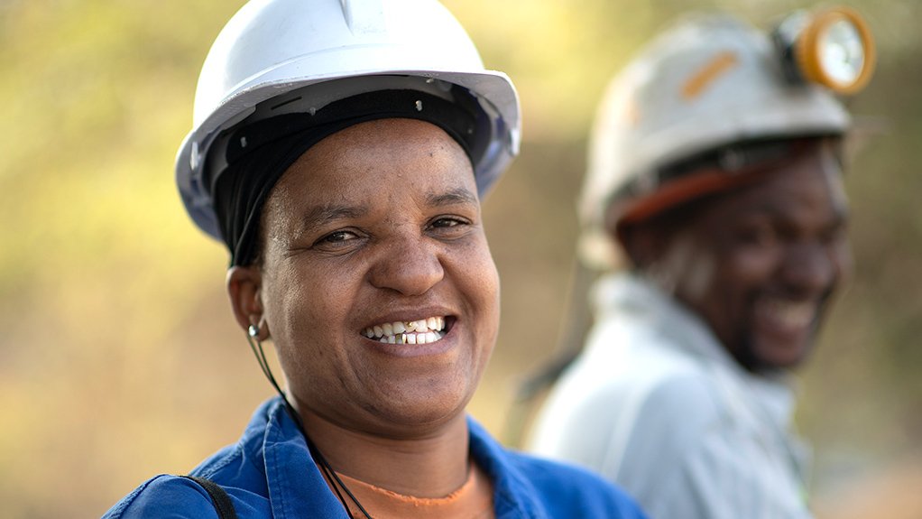 An image depicting a smiling woman wearing a white hardhat