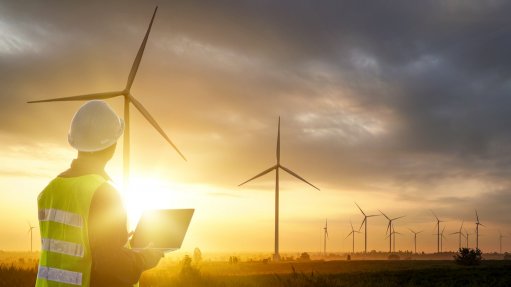 Image of silhouette of a man with wind turbines in the background