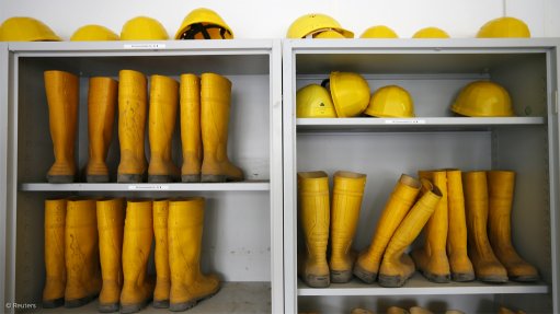 Image shows work boots and hard hats stacked 