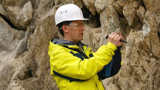 A man in a hard hat at the exploration face looking at a rock